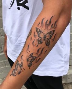 a man's arm with two butterflies on it and flames coming out of the back