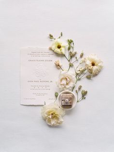 a wedding ring and flowers on a white background