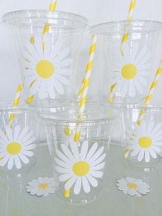 six plastic cups with yellow and white paper straws in them, decorated with daisies