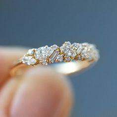 a close up of a person's hand holding a gold and white diamond ring