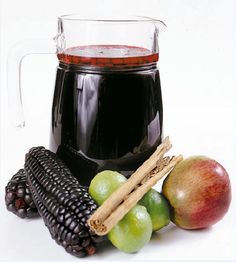 a glass mug filled with black liquid next to fruit and an ear of corn on the cob