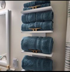 towels are hanging on the wall in a bathroom with white shelving and gold hardware