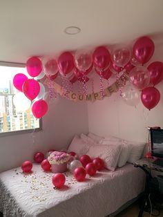 balloons and streamers fill the air above a bed in a room decorated for a birthday