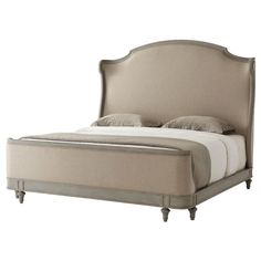 an upholstered bed with beige linens and pillows