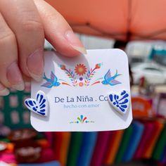 a person holding up a business card in front of colorful umbrellas at an outdoor market