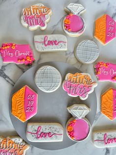 some decorated cookies are on a plate with pink and orange frosting, one is for valentine's day