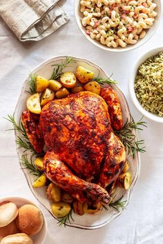 a turkey and potatoes on a white tablecloth next to two bowls of stuffings