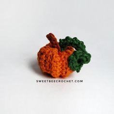 an orange and green crocheted apple sitting on top of a white surface with the words sweetbee crochet com written below it