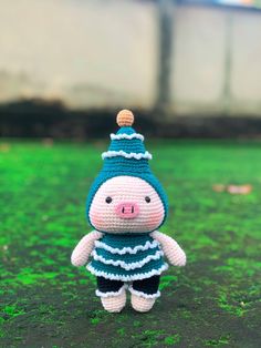 a small crocheted pig wearing a blue and white striped shirt with a green hat