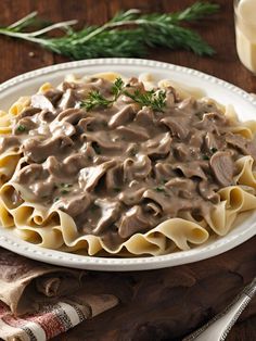 a white plate topped with pasta covered in gravy next to a glass of milk