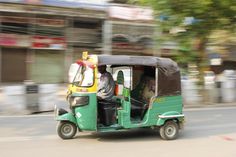 a green and yellow golf cart driving down the street