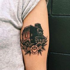 a woman's arm with a house and flowers tattoo on the left side of her arm