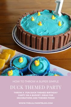 a birthday cake with blue frosting and yellow rubber ducks on it, next to some cupcakes