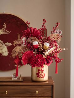 a vase filled with red flowers on top of a wooden table