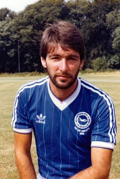 a man sitting on top of a soccer field wearing a blue shirt and white shorts