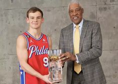 an older man holding a basketball trophy next to a young boy