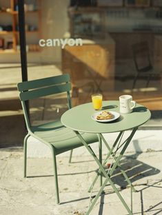 a small table with a plate of food on it next to a green folding chair