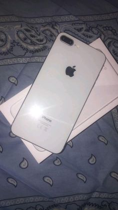 two iphones sitting on top of each other on a blue and white bed spread