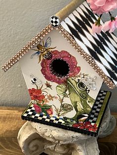 a birdhouse with flowers and insects painted on it