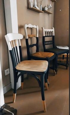 three black and white chairs sitting next to each other in front of a wall with shelves on it