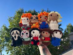 a hand holding a bunch of small crocheted dolls