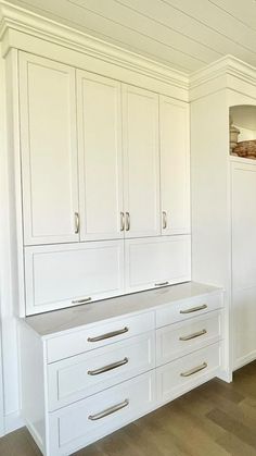 an empty kitchen with white cabinets and drawers in the center, along with wood flooring