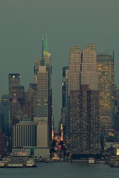 the city skyline is lit up at night, as seen from across the water in new york