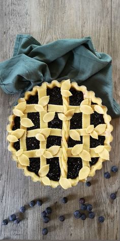 an uncooked pie sitting on top of a wooden table next to blueberries