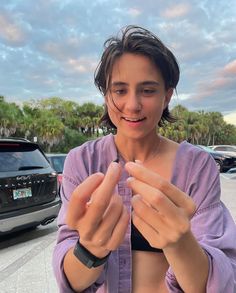 a woman in a purple shirt is holding her hands together