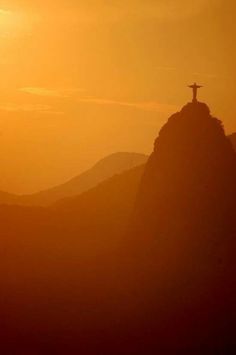 the silhouette of a person standing on top of a mountain