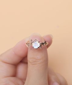 a woman's hand holding an engagement ring with a white diamond in the middle