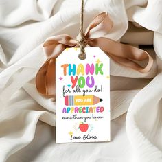 a thank you tag hanging from a string on top of a bed covered in white sheets