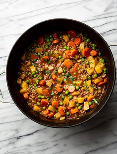 a pot filled with peas, carrots and other vegetables