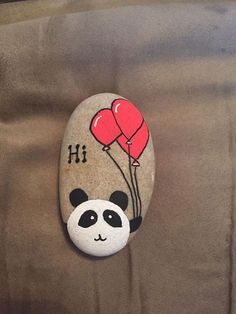 a rock with a panda holding balloons on it