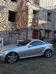 a silver sports car parked in front of a stone building