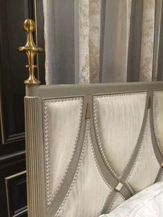 the headboard and foot board of a bed with white linens, gold trim