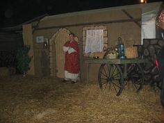 a man dressed as santa clause standing in front of a small house with hay on the ground