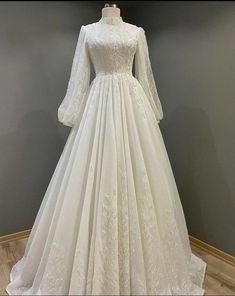 a white wedding dress with long sleeves on display