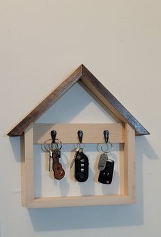 a house shaped key holder with keys hanging from it's sides and on the wall