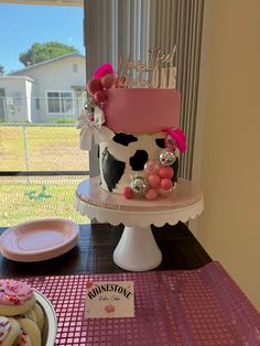 a pink and black cake sitting on top of a table next to doughnuts