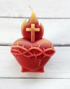 a small red candle with a cross on it