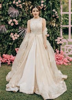 a woman standing in front of a flower covered arch wearing a wedding dress with an open back