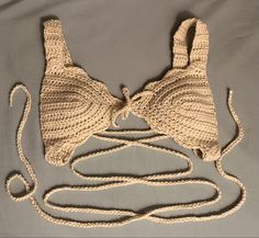 two crocheted handbags tied together on top of a gray cloth covered surface