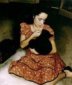 a woman sitting on the floor holding a black cat