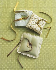 three small purses are sitting on a green surface with gold ribbon and ribbons around them