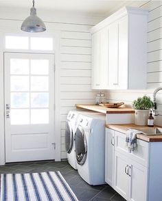 a washer and dryer in a white laundry room next to a kitchen counter