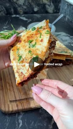 a person holding up a slice of pizza on a cutting board