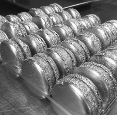 a tray filled with lots of donuts on top of a metal counter covered in frosting