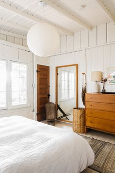 a bedroom with white walls and wooden furniture