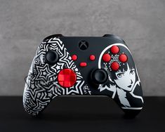 a black and white controller with red buttons on it's side, next to a gray wall